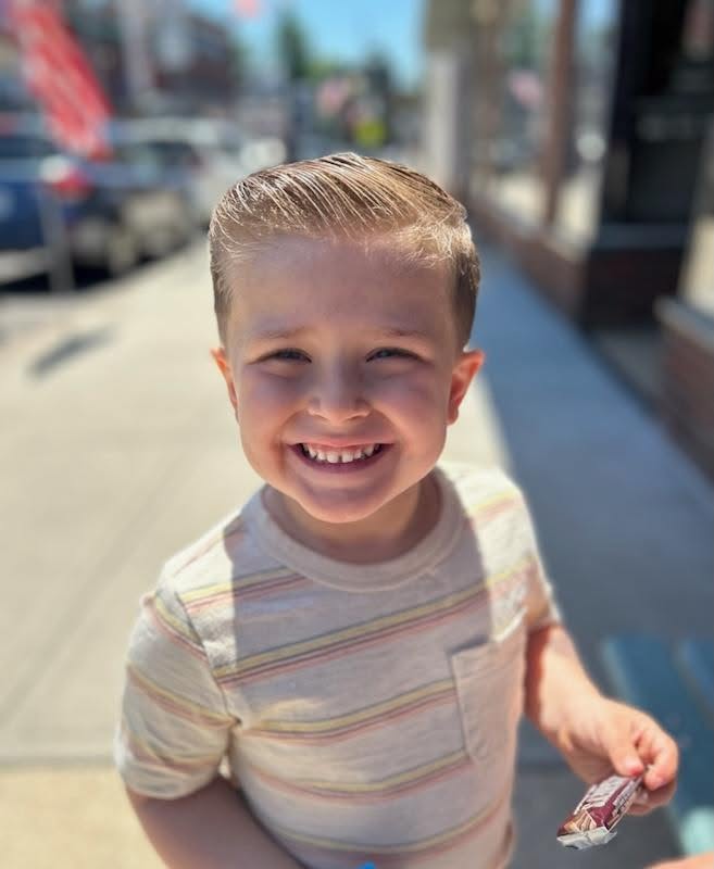 Young customer outside Willie's, big smile, holding a treat