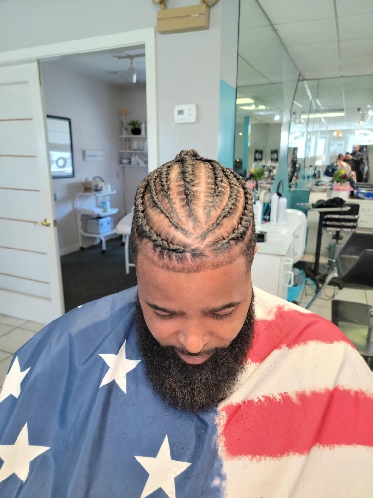 Client looking down showing cornrow pattern and shaped beard with flag cape